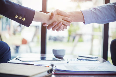 Cropped image of business coworkers shaking hands over desk in office