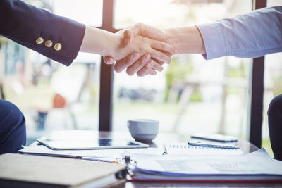 Cropped image of business coworkers shaking hands over desk in office