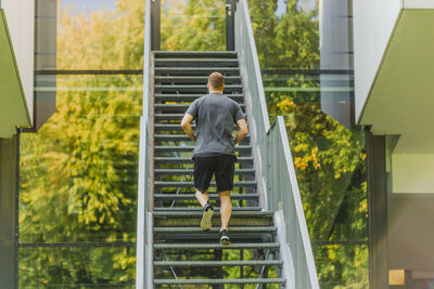 Rear view of man walking on staircase of building