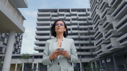 Portrait of young woman standing against building