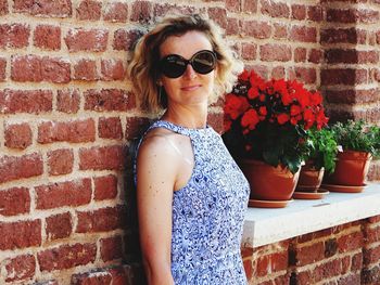 Portrait of young woman standing against brick wall