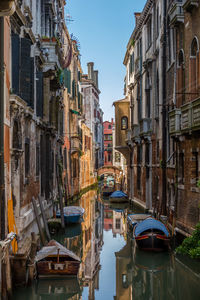 Boats moored in canal amidst buildings