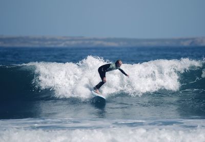 Man surfing in sea against sky