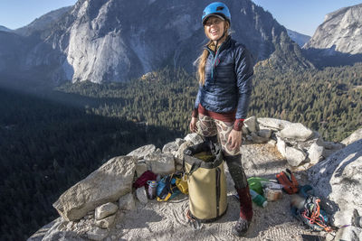 A young woman climber smiles as she stands on last night's bivy ledge