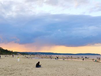 People on beach against sky during sunset