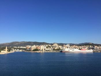 Scenic view of sea by city against clear blue sky