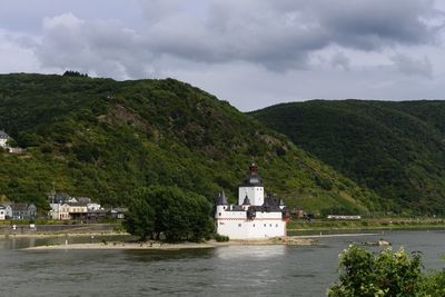 Built structure by river against sky