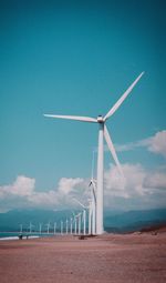 Wind turbines on field against sky