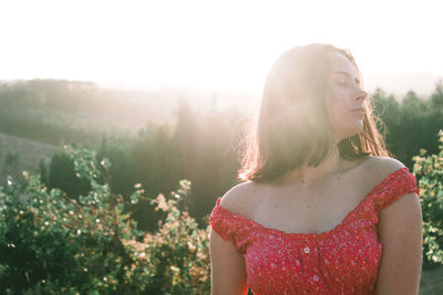 Woman with eyes closed in forest against clear sky