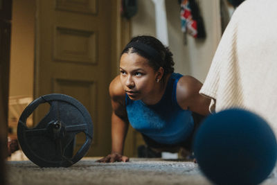 Determinant teenage girl practicing push-ups at home