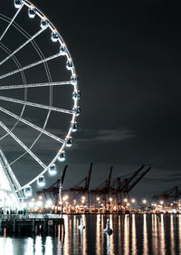 Low angle view of illuminated ferris wheel against sky at night