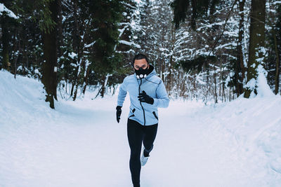 Portrait of male athlete running on snow covered field