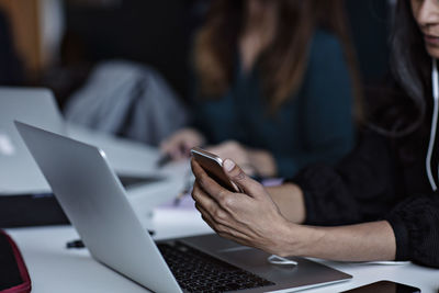 Midsection of business woman using technologies at conference table in board room