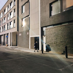 Rear view of people walking on street by buildings