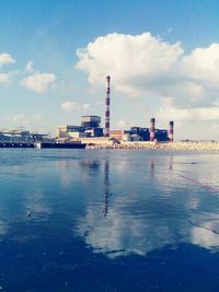 Factory by sea against sky