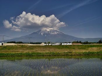 Scenic view of field by lake against sky