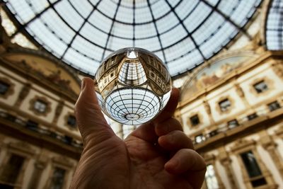 Hand holding crystal ball against historical buildings 