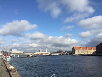 Bridge over river by buildings in city against sky