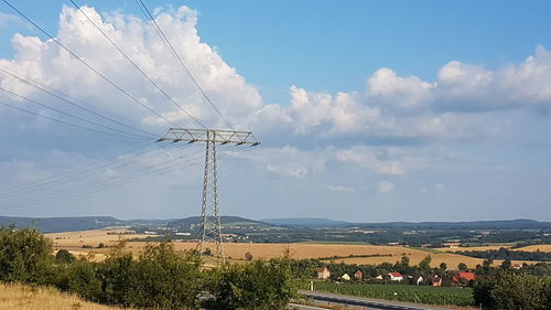 Electricity pylon on field against sky