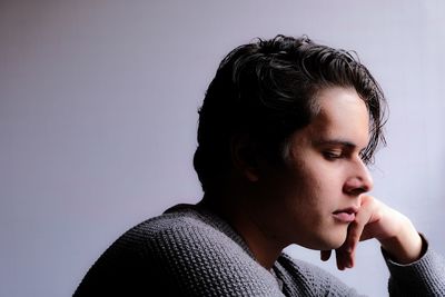 Thoughtful young man looking away against white background