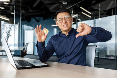 Portrait of young man using mobile phone while sitting at office