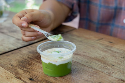 Cropped image of person holding drink on table