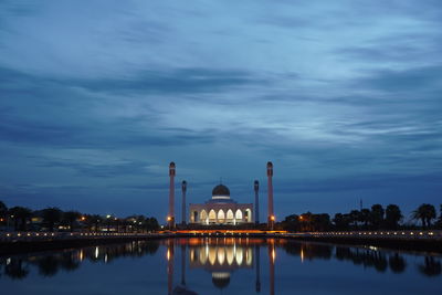 Mosque reflecting in lake against sky at dusk