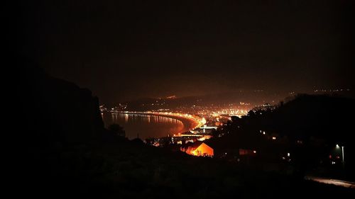 Illuminated bridge over river against sky at night