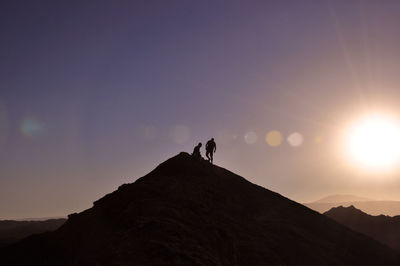 Silhouette of people standing on mountain peak