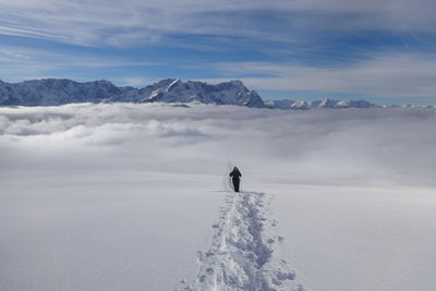 Person on snowcapped mountain against sky