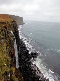 Scenic view of waterfall against sea against cloudy sky