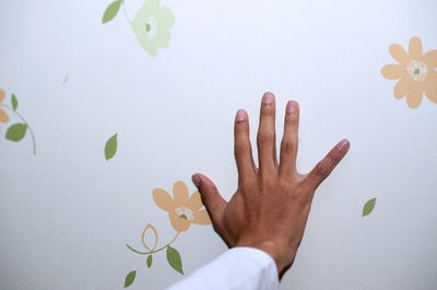 Cropped hand of men gesturing against white wall