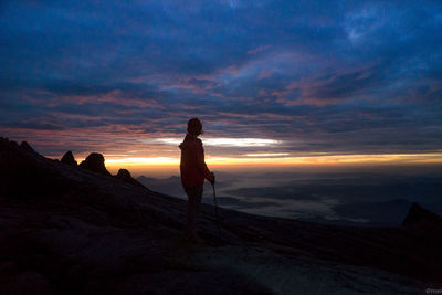 Silhouette woman standing on land against sky during sunset