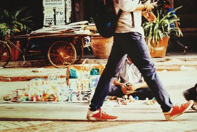 Low section of man walking by vendor on footpath 