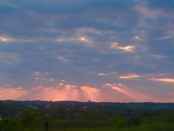 Scenic view of landscape against dramatic sky at sunset