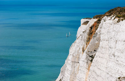 View of rock formation by sea against blue sky