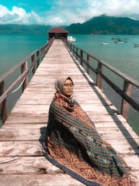 Portrait of man on pier by sea against sky