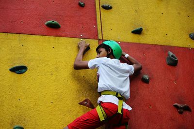 Low angle view of boy climbing wall