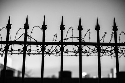 Low angle view of silhouette fence against sky