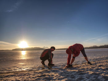 Heterosexual couple, woman and man working out near winter lake. morning exercise on lake beach.