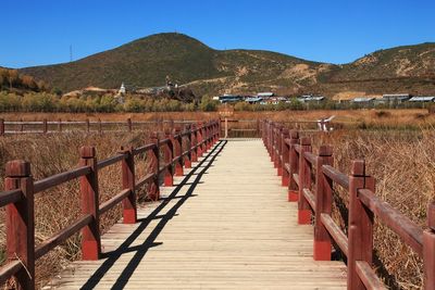 View of wooden walkway leading towards mountains