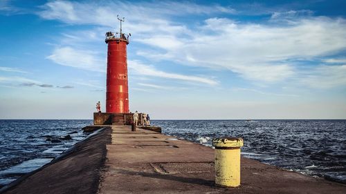Lighthouse by sea against sky