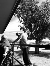 Man and bicycle on tree against sky