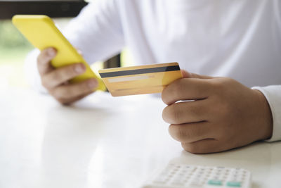 Midsection of man using smart phone on table