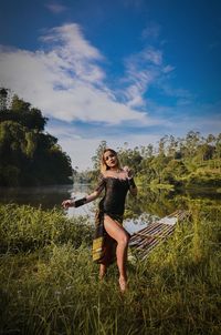 Fashionable woman standing on field against sky