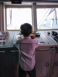 Rear view of boy looking through window