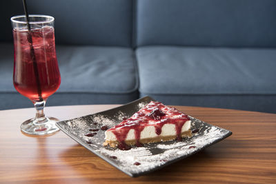 Close-up of cheesecake in plate with strawberry drink on table
