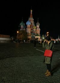 Woman at illuminated temple against sky at night