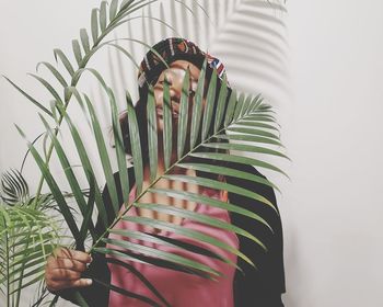 Woman holding umbrella standing against plants