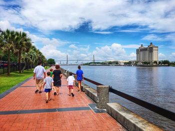 Rear view of people walking on water against sky